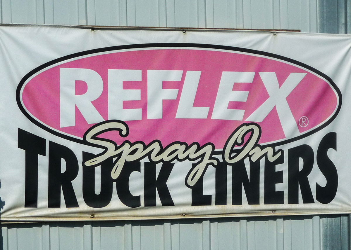 Reflext spray on truck liners logo sign outside of THEE Auto Body Shop